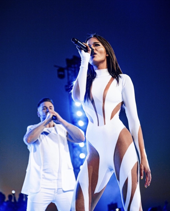 Pauline tijdens een live optreden, zingend op het podium met een energieke en sprankelende uitstraling