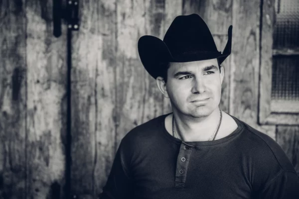 Robby Longo live op het podium met cowboyhoed en gitaar, zingend met diepe stem tijdens een sfeervol country-optreden