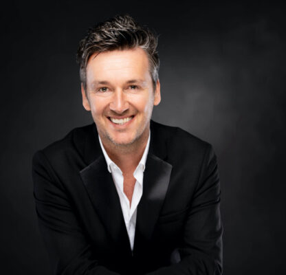 Davy Gilles zingt live op podium met sfeervolle belichting en enthousiaste toeschouwers