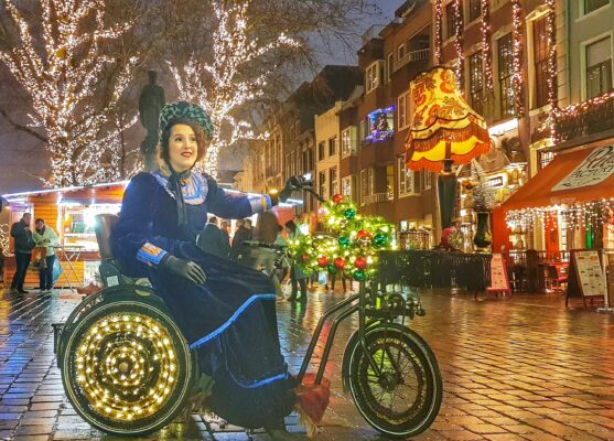 Dickens zangeres op kerstfiets in Victoriaanse kledij die live kerstliederen zingt