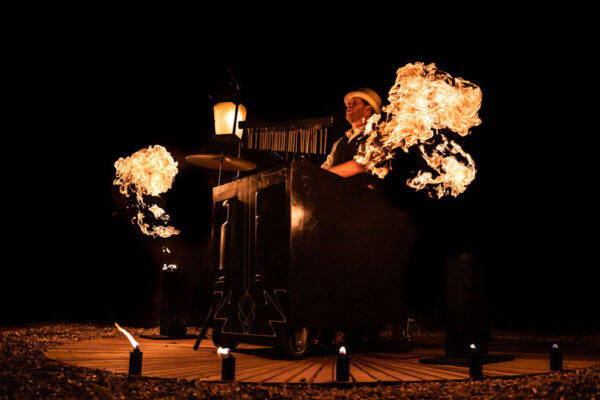 Kanza Mees speelt live muziek terwijl vlammen de lucht verlichten bij Muzikaal Vuur onthaalact
