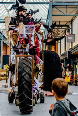 Gigantische rijdende spinnenwagen omringd door webben, rook en Halloween-performers