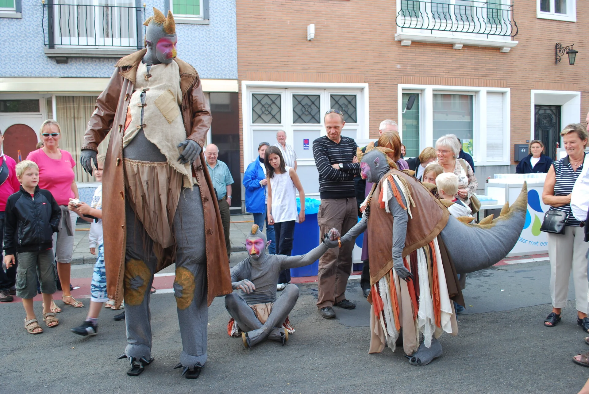 Steltloper in dino-kostuum met acrobatisch kind in kooi tijdens straatanimatie